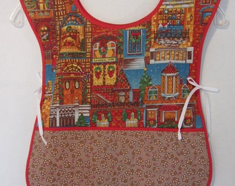 Puede incluir: Un delantal rojo de Navidad con un patrón de casa de jengibre y un bolsillo con estampado de hombre de jengibre. El delantal tiene lazos blancos.