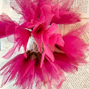 May include: A bouquet of pink, delicate, dried leaves arranged on a stack of books. The leaves are translucent and have a delicate vein pattern.