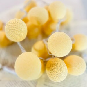 May include: A string of warm white cotton ball lights, ideal for adding a soft glow to any space. The lights are strung together with a clear wire and are battery operated.
