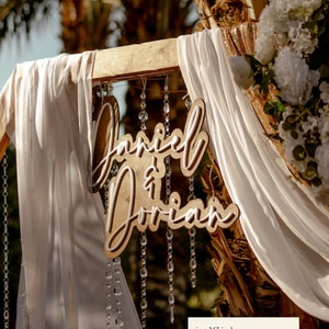 Couple's last name wooden double layer sign hanging on wedding arch.