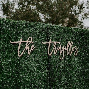 May include: A green artificial hedge backdrop with the words "the" and "Truillos" written in cursive on it.