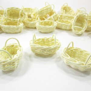 Close-up view of three handcrafted miniature oval wicker baskets showing natural woven textures and dual side handle details.