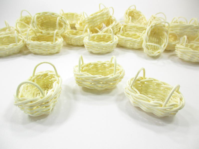 Close-up view of three handcrafted miniature oval wicker baskets showing natural woven textures and dual side handle details.