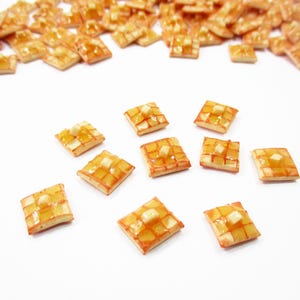 May include: An overhead shot of numerous small, square, golden-brown pastries with a lattice design and a glossy glaze. Some pastries are scattered, while others are grouped together on a white surface. The pastries have a light-colored filling.