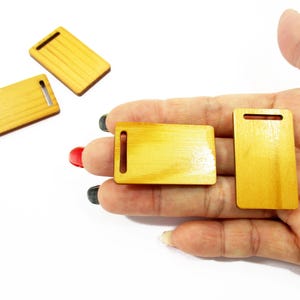 Adult palm holding handcrafted 1:12 scale miniature wooden boards, highlighting the realistic wood texture for mini collectors.