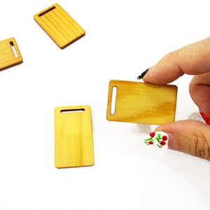 Fingers holding a handcrafted 1:12 scale miniature wooden board, showing detailed 23x38mm dimensions for dollhouse kitchens.