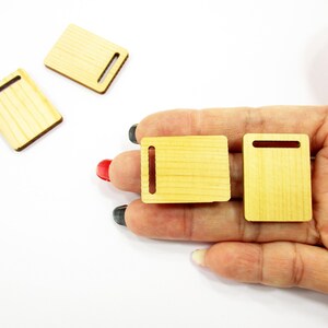 Palm holding two 30x23mm handcrafted 1:12 scale miniature wooden boards showing the smooth natural finish and artisan quality.