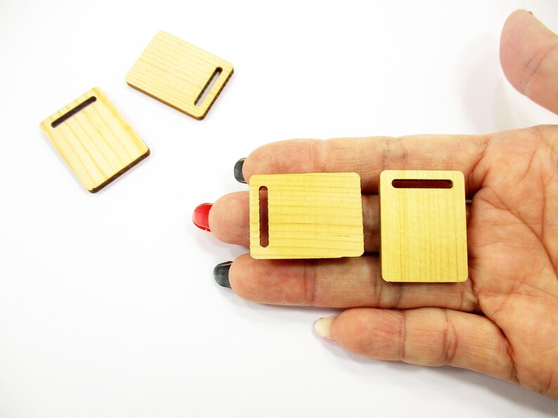 Palm holding two 30x23mm handcrafted 1:12 scale miniature wooden boards showing the smooth natural finish and artisan quality.