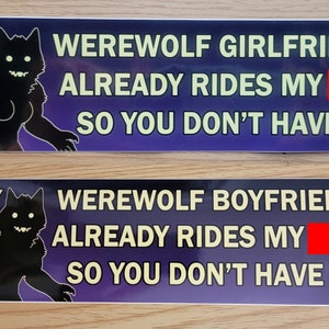 May include: Two bumper stickers with a purple and black background. The top sticker reads "MY WEREWOLF GIRLFRIEND ALREADY RIDES MY SO YOU DON'T HAVE TO." The bottom sticker reads "MY WEREWOLF BOYFRIEND ALREADY RIDES MY SO YOU DON'T HAVE TO."