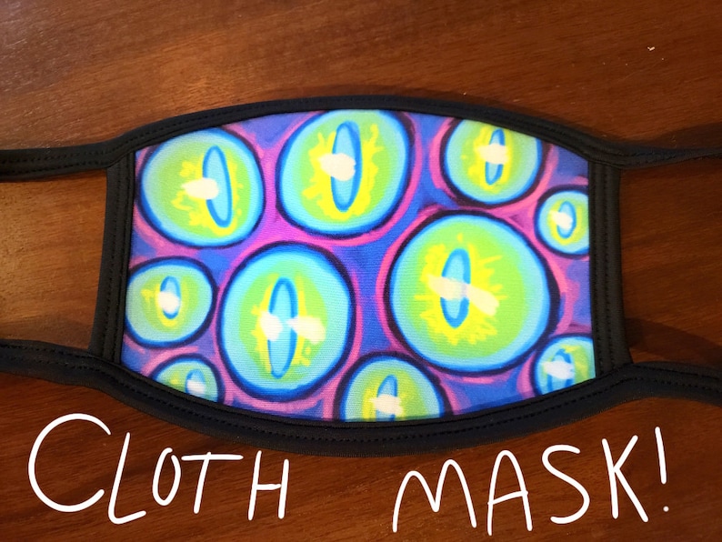May include: A black cloth face mask with a colorful print of blue, green, yellow, and purple eyes. The mask has elastic ear loops.