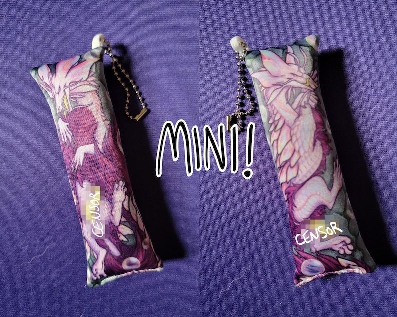May include: Two rectangular, mini-sized fabric keychains with a fantasy dragon design. The keychains feature a chain and a white top. The text "MINI!" is in white, and the word "CENSOR" is printed on the keychain.