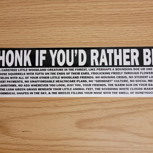 Peut inclure: Autocollant noir et blanc avec le texte "HONK IF YOU'D RATHER BE" en grandes lettres blanches. Le texte ci-dessous indique "Une petite créature des bois insouciante dans la forêt, comme peut-être une biche bondissante ou l'un de ces écureuils avec des touffes au bout des oreilles, gambadant librement à travers des champs fleuris avec tous vos autres petits amis des bois. Pas de crise du logement, pas de remboursement de prêt étudiant, pas de plans de santé abordables, pas de culture "grindset", pas d'algorithmes de médias sociaux, pas de publicités où que vous regardiez ; juste vous, vos amis, le soleil chaud sur le dos, l'herbe verte luxuriante sous vos petits pieds d'animaux, les nuages blancs qui filent en faisant des formes fantaisistes dans le ciel, et la brise qui remplit votre nez de l'odeur du chèvrefeuille."