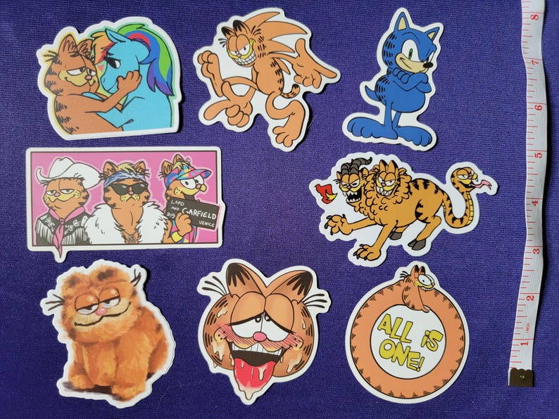May include: A collection of seven die-cut vinyl stickers featuring various cartoon cat illustrations, including a multi-headed creature, a cat-pony hybrid, and a circular design with the text ALL IS ONE, displayed next to a white measuring tape showing 8 inches.
