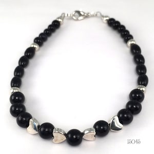 May include: Black beaded bracelet with silver heart charms and a silver clasp. The bracelet is 15045.