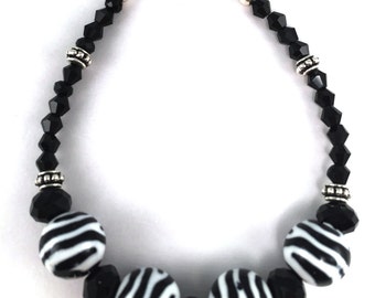 Black and white zebra print beads with black faceted crystals and silver tone studded spacers stacking beaded bracelet