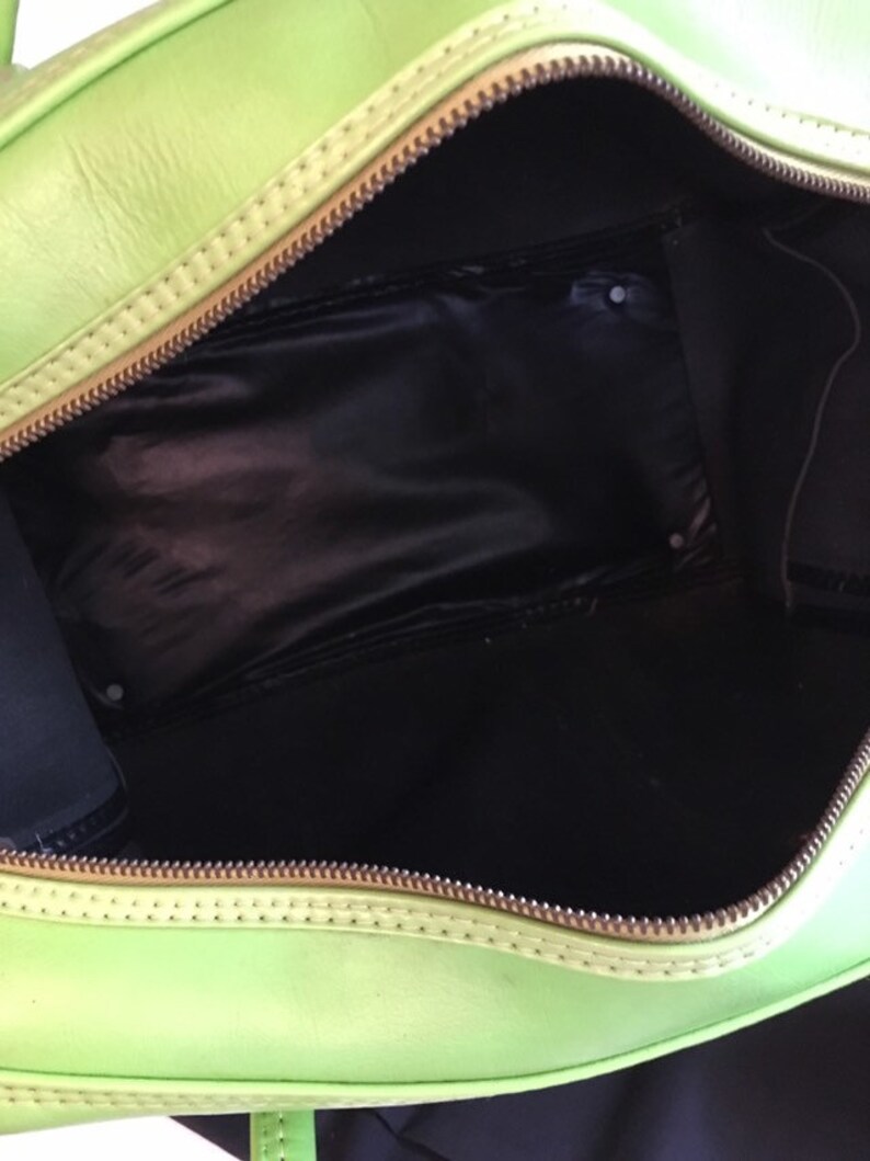 May include: A bright green leather travel bag with a zipper closure and a black fabric lining. The bag is open and the interior is visible.