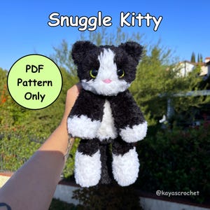 Puede incluir: Un peluche de gato en blanco y negro con el texto "Snuggle Kitty". El gato tiene ojos verdes y una nariz rosa. También es visible un círculo verde con el texto "PDF Pattern Only".