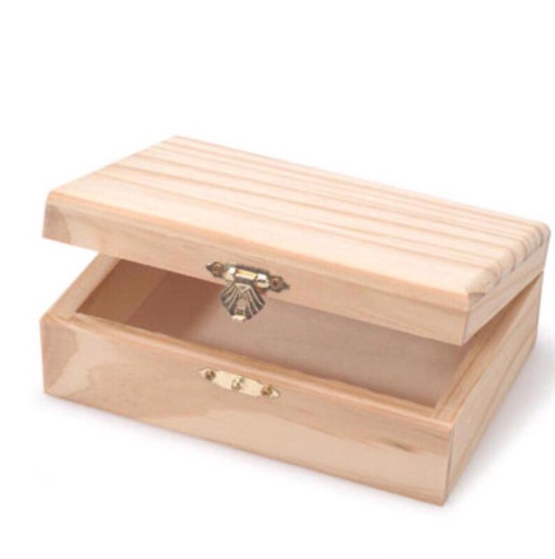 Puede incluir: Una caja de madera natural con tapa abatible y cierre de lat&oacute;n. La caja est&aacute; abierta y vac&iacute;a.