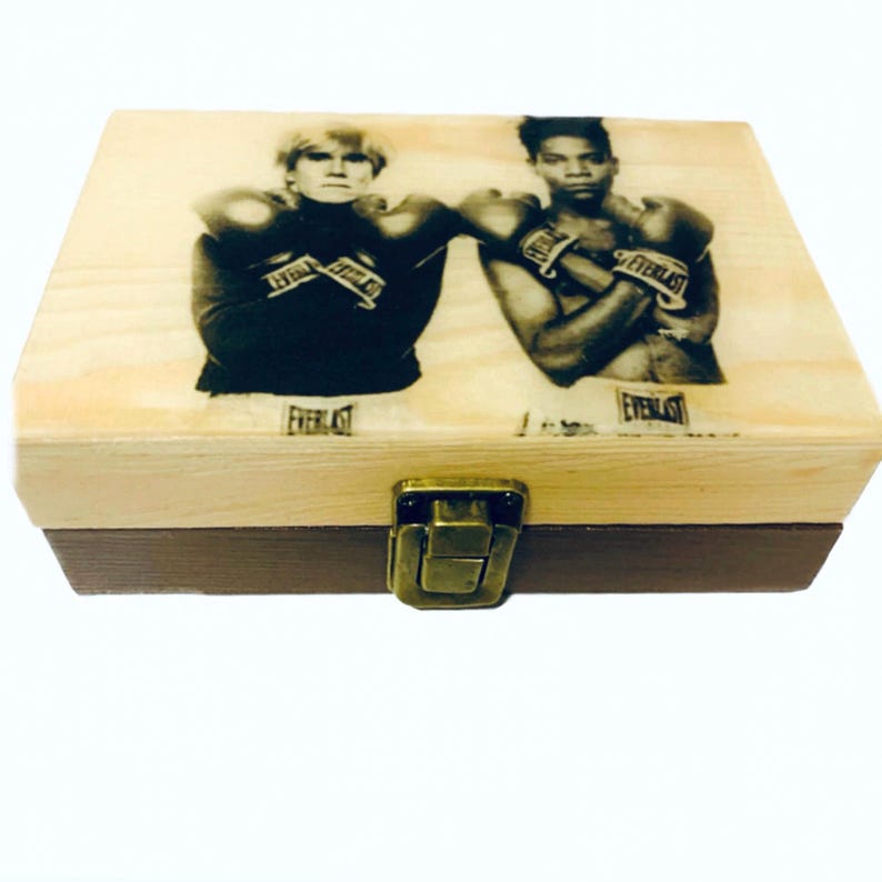 Puede incluir: Una caja de madera con tapa con bisagras y cierre de lat&oacute;n. La tapa presenta una foto en blanco y negro de dos hombres con guantes de boxeo. El texto "Everlast" es visible en los guantes y la parte inferior de la caja.