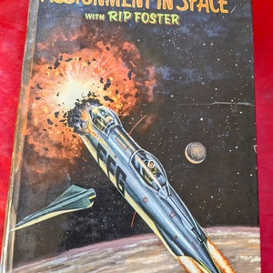 May include: A vintage book cover with the title "Assignment in Space" with Rip Foster. The cover features a futuristic spaceship flying through space with a fiery explosion behind it.