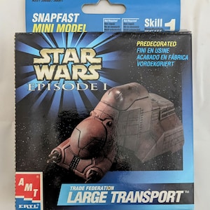 May include: A box for a Star Wars Episode I Trade Federation Large Transport Snapfast Mini Model kit. The box features a picture of the transport, which is brown and gray. The box is blue and white and has the words "Star Wars Episode I" and "Trade Federation Large Transport" on it.
