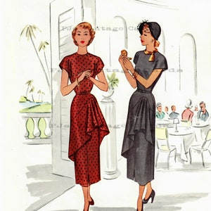 May include: Two women in 1950s style dresses stand in a hallway. The woman on the left is wearing a red dress with white polka dots and a ruffled skirt. The woman on the right is wearing a gray dress with a ruffled skirt and a black hat. They are both smiling and looking at each other.