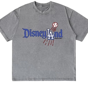 May include: A gray t-shirt with the text "Disneyland LA Resort" in blue and white, with a baseball graphic. The shirt has a vintage, washed look.