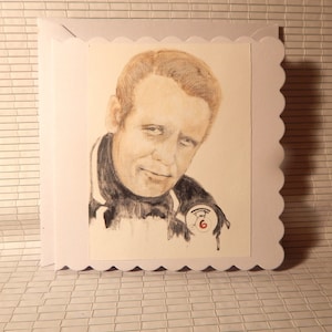 May include: A black and white drawing of a man with a serious expression. He is wearing a dark turtleneck sweater and a small badge with the number 6 on it.