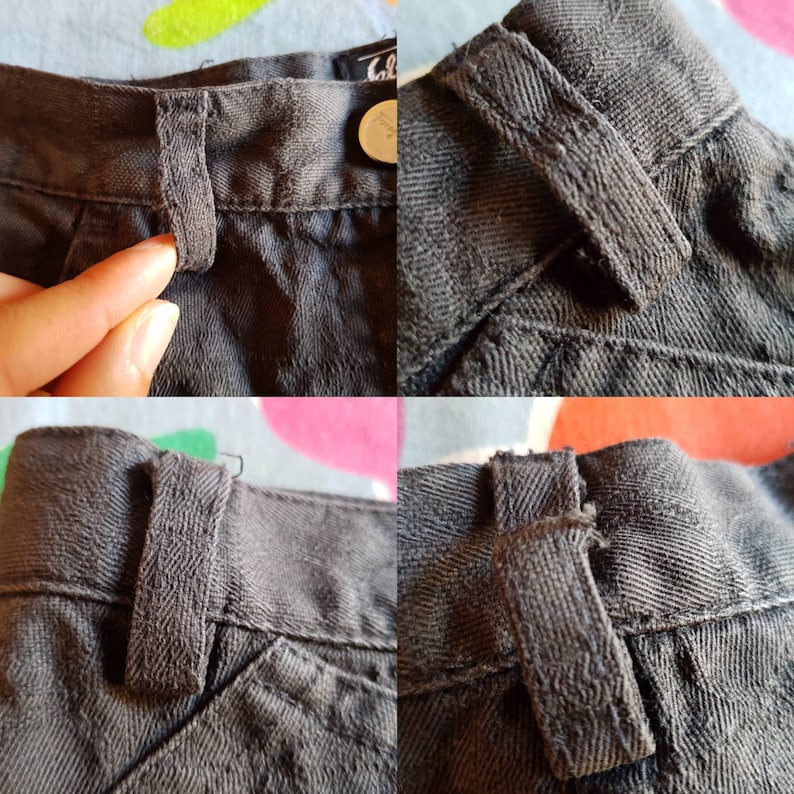 May include: Close-up of a dark grey fabric with a sewn-in loop. The loop is made of the same fabric and is stitched to the fabric with a zig-zag stitch.