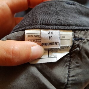 May include: A white tag with black text that reads "100% COTTOL", "N 136180", "44", "10", "(CO)", and "MADEINITALY".