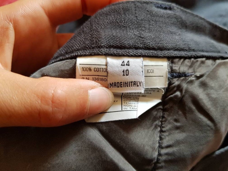 May include: A white tag with black text that reads "100% COTTOL", "N 136180", "44", "10", "(CO)", and "MADEINITALY".