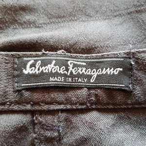 May include: A black fabric label with white text that reads "Salvatore Ferragamo Made in Italy".