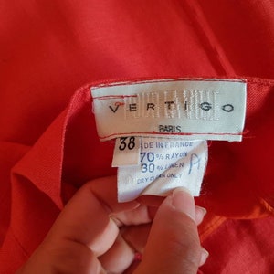 May include: A red linen blend skirt with a white label that reads "VERTIGO PARIS" and size 38. The label also includes care instructions: "Made in France, 70% Rayon, 30% Linen, Dry Clean Only."