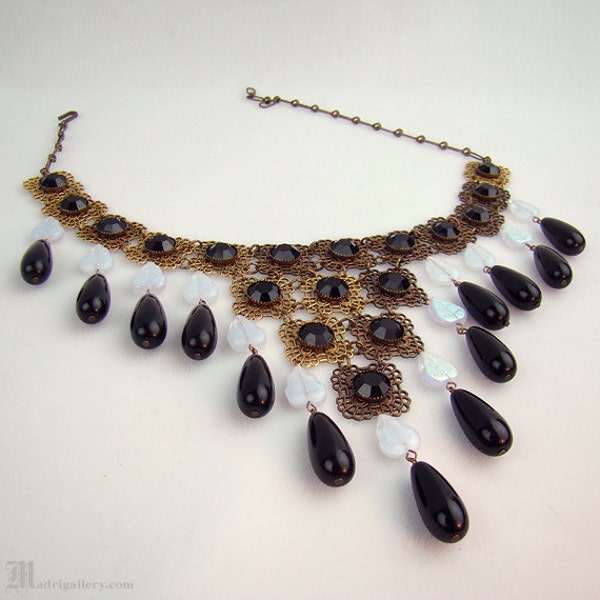 Antieke art deco halsketting met gefacetteerde zwarte glazen kristallen in goudkleurig filigraan metaal, opaalachtig bladvormig glas en grote zwarte glazen druppels.