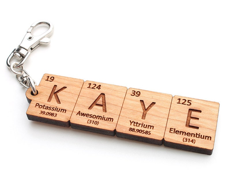 Peut inclure: Porte-cl&eacute;s en bois avec un fermoir en m&eacute;tal argent&eacute;. Le porte-cl&eacute;s est compos&eacute; de quatre tuiles en bois, chacune avec une lettre et un symbole et un nom d'&eacute;l&eacute;ment chimique. Les tuiles &eacute;pellent le nom "KAYE".