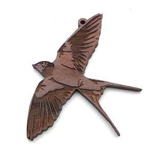 May include: A wooden cutout of a brown swallow in flight. The swallow is detailed with wood grain and has a hole at the top for hanging.