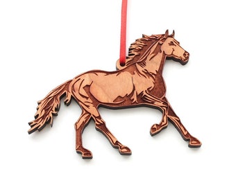 May include: A wooden horse ornament in a running pose, with detailed carving. The horse is light brown with darker brown accents, and hangs from a red ribbon. The ornament is suitable for a Christmas tree or other seasonal display.