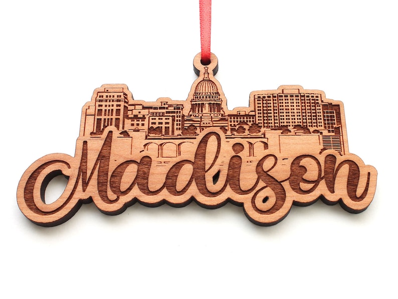 May include: Wooden ornament featuring a laser-engraved silhouette of the Madison, Wisconsin skyline, including the state capitol building. The word "Madison" is written in a decorative script below the skyline.