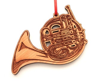 May include: A wooden ornament shaped like a French horn. The ornament is a light brown color and has a detailed design.