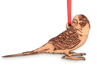 May include: A wooden ornament of a brown and white parakeet with a red ribbon attached.