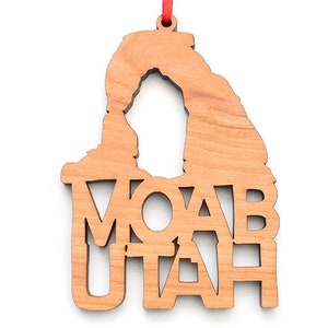 May include: Wooden ornament shaped like Delicate Arch in Moab, Utah. The ornament is made of light brown wood and has the words "Moab Utah" cut out of the bottom.