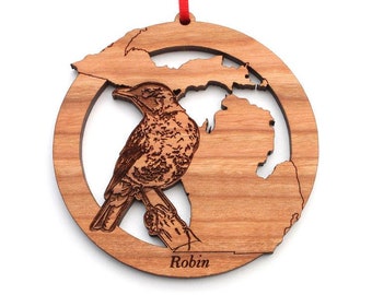 May include: A wooden ornament featuring a robin bird and an outline of the state of Michigan. The ornament is brown and has the word "Robin" inscribed at the bottom.