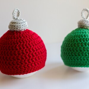 May include: Two crocheted Christmas ornaments, one red and one green, with white tops.