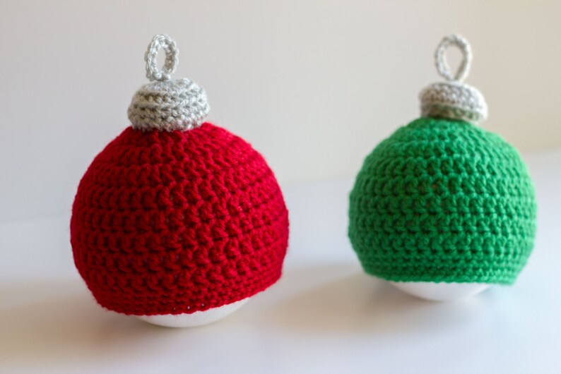 May include: Two crocheted Christmas ornaments, one red and one green, with white tops.
