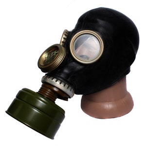Op de afbeelding: Een zwart gasmasker met een groen filter en een transparant plastic oogstuk. Het masker zit op een mannequinhoofd.