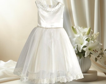 May include: A white tulle and satin dress with a beaded neckline and lace trim. The dress has a full skirt and is perfect for a special occasion.