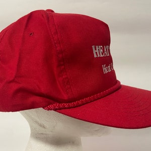May include: Red baseball cap with a white rope trim and white embroidered text that reads "HEAT & COOL" and "Heat & Cool".