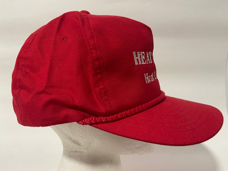 May include: Red baseball cap with a white rope trim and white embroidered text that reads "HEAT & COOL" and "Heat & Cool".