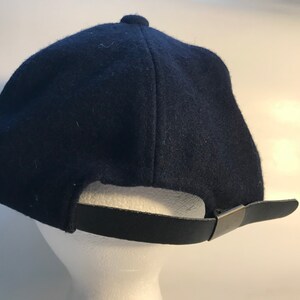 Puede incluir: Una gorra de b&eacute;isbol azul oscuro con una correa ajustable negra y una hebilla plateada.