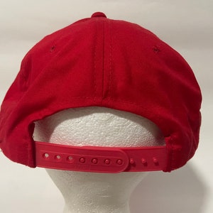 May include: Red baseball cap with a red adjustable strap at the back.
